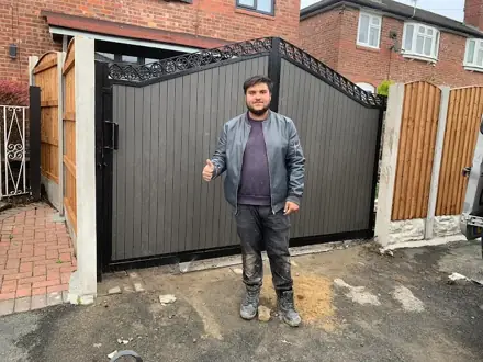 Grey composite gate with an arched black frame, a man standing in front of it