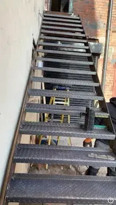 Steel external staircase with chequer-plate treads beside a building