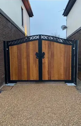 Timber-infill double gates in a black decorative frame on a resin driveway